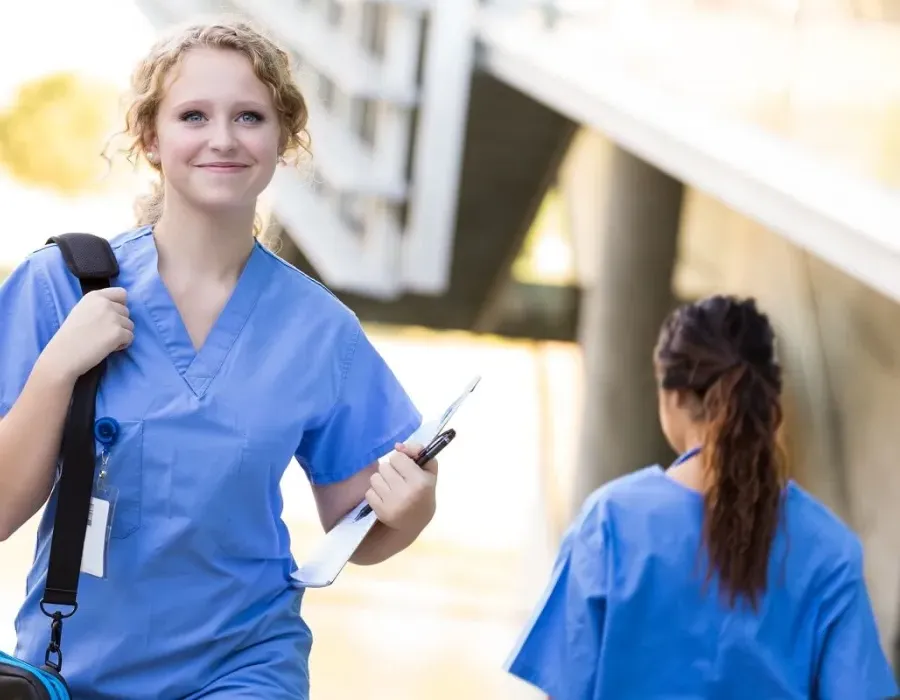 Smiling nursing student in scrubs walking to class